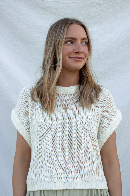 Woman wearing a white knit top against a plain background