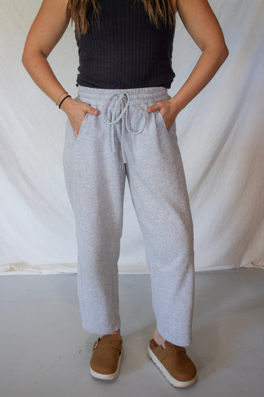 Person wearing gray sweatpants and a black top against a white background