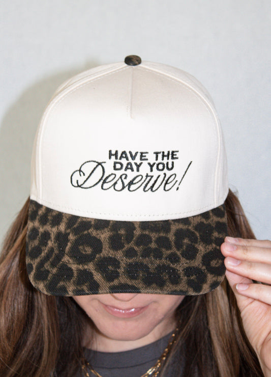 Trucker hat with leopard print brim and motivational text on a plain background