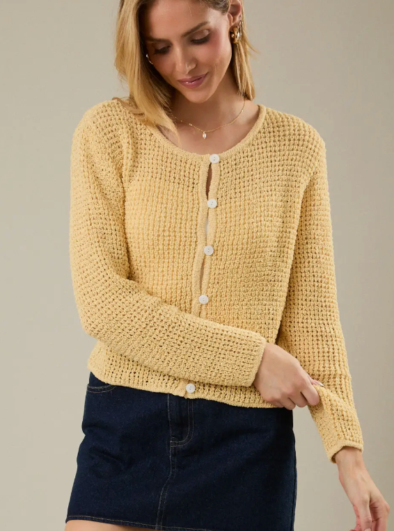 Woman wearing a yellow knitted cardigan against a neutral background