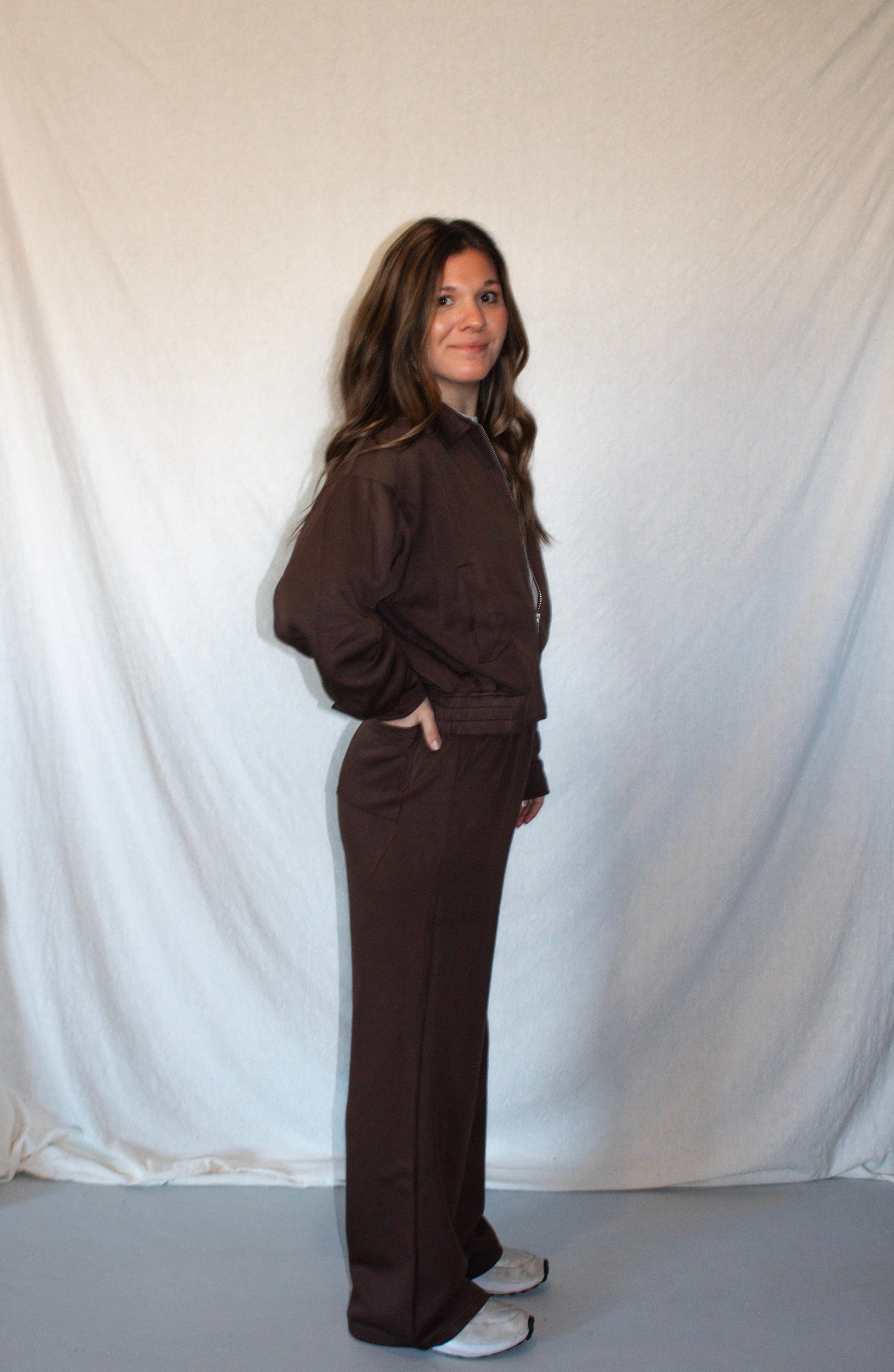 Person wearing a brown outfit standing against a plain white background