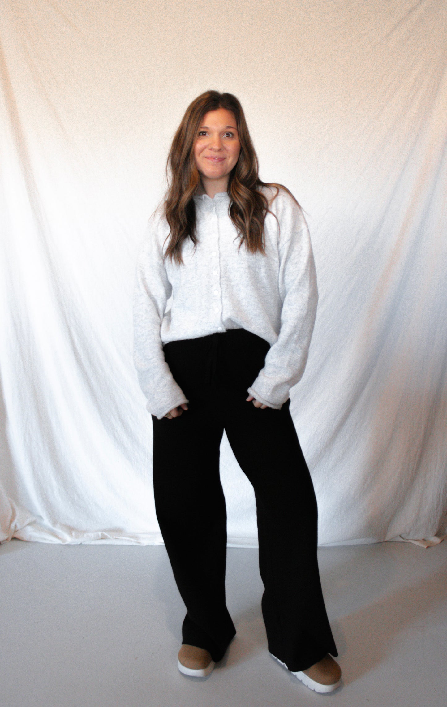 Person wearing a white shirt and black pants against a plain background