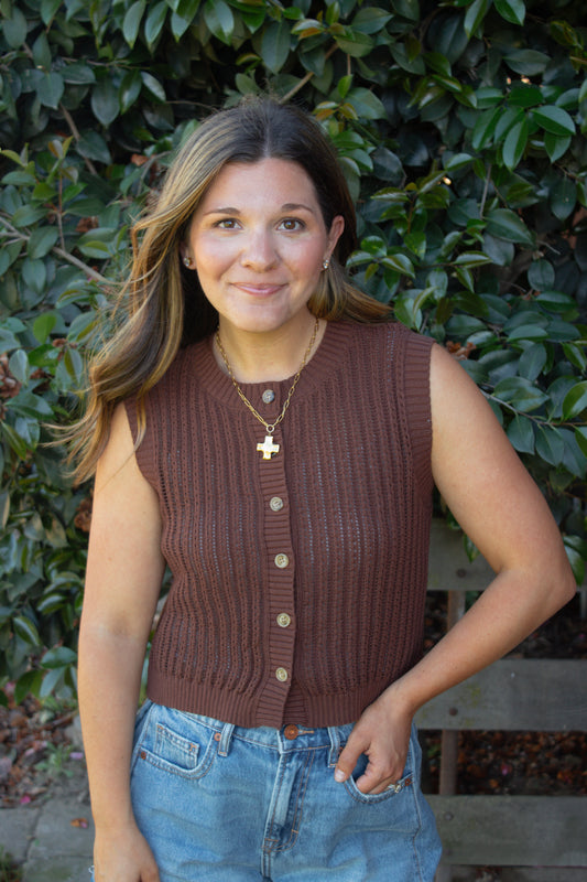 Woman wearing a brown knitted vest with a leafy background