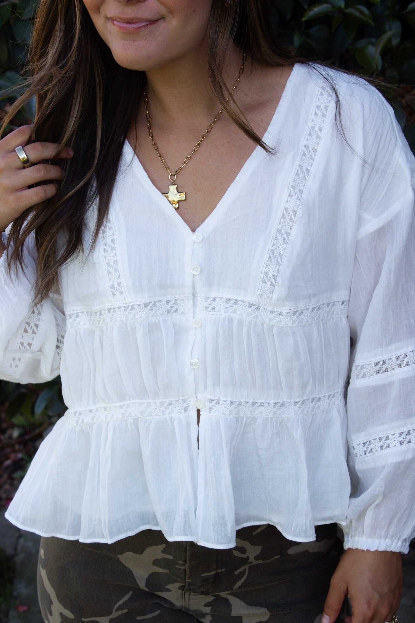 White blouse with lace details worn by a person, with a blurred background