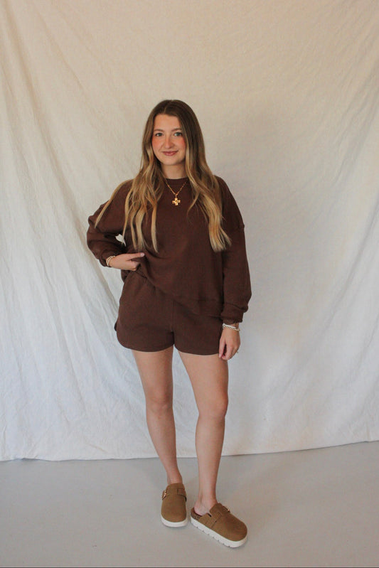 Person wearing a brown outfit against a white backdrop