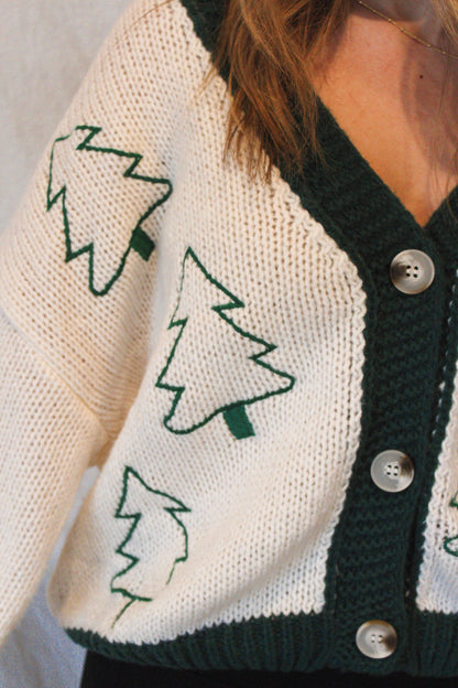 Close-up of a person wearing a cardigan with tree patterns and buttons.