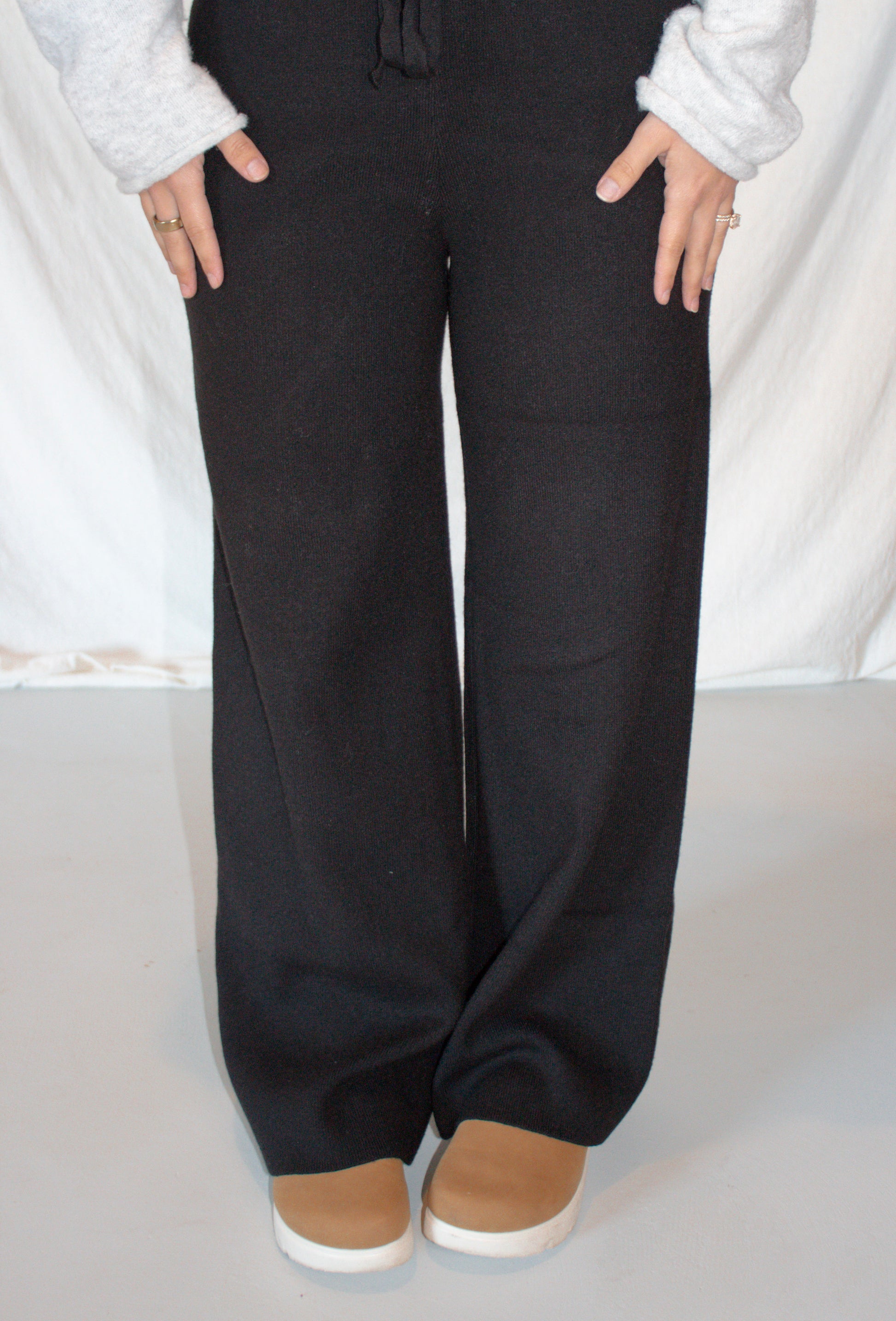 Person wearing black wide-leg pants with a white background