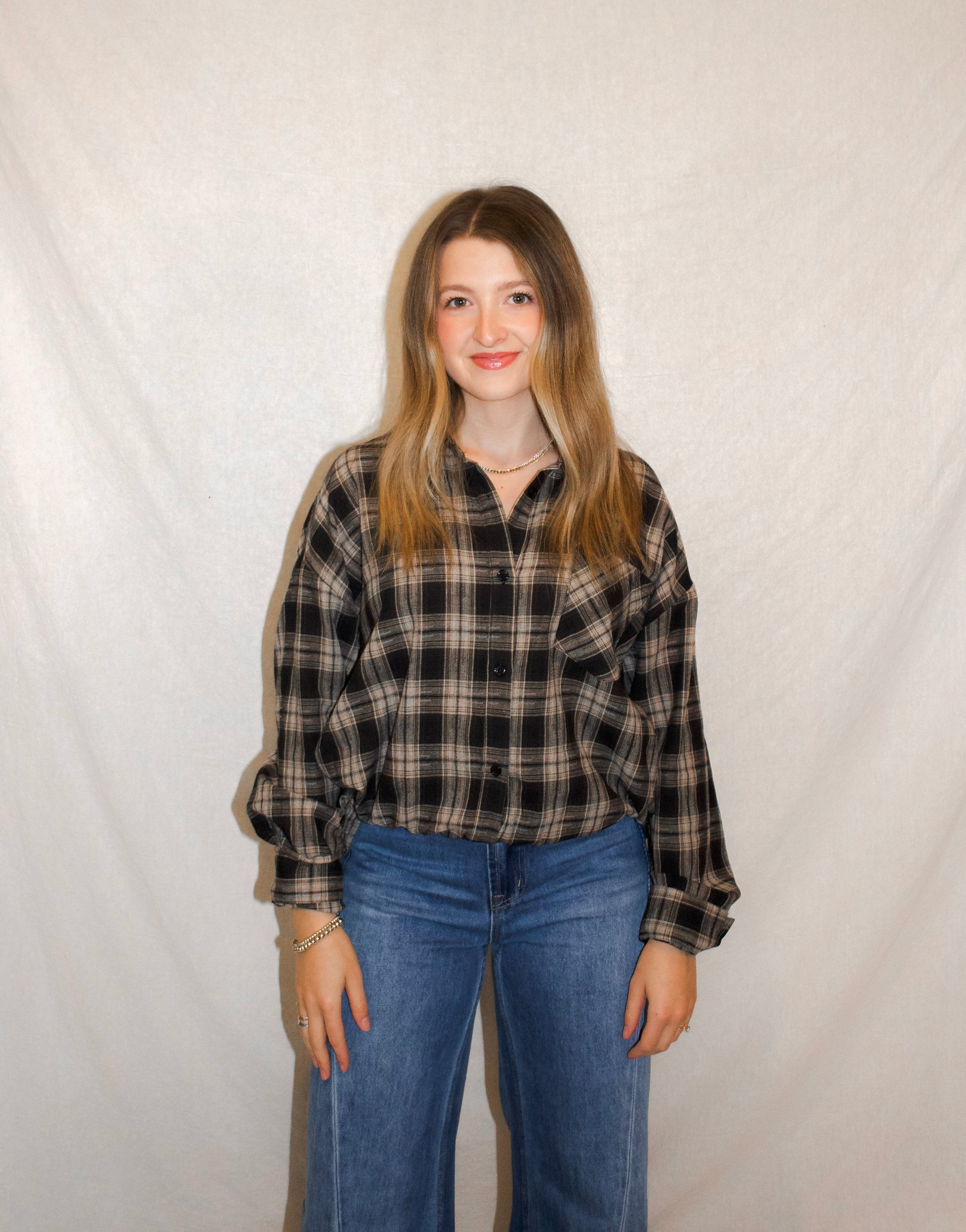 Person wearing a plaid shirt and jeans against a plain background
