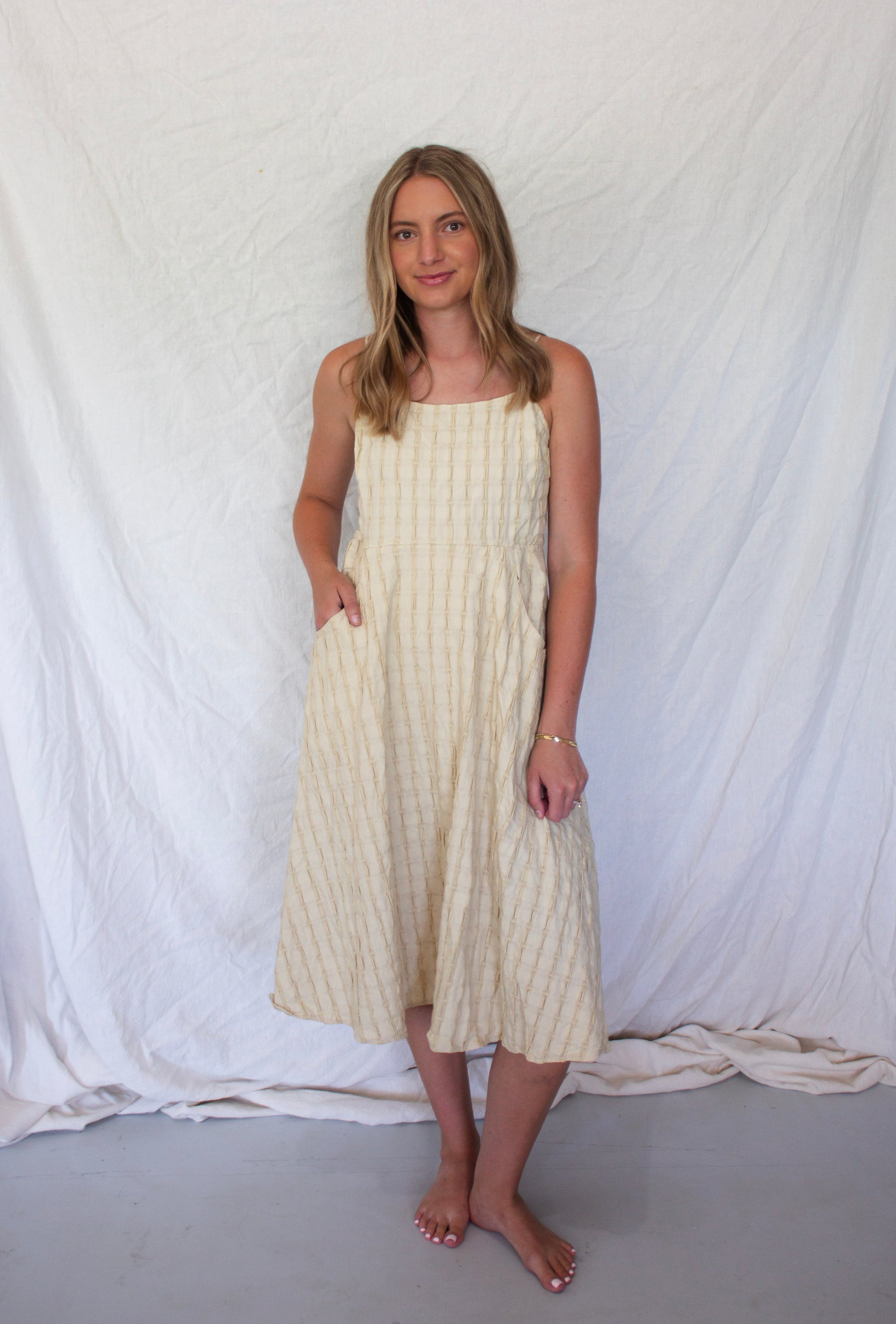 Woman wearing a white dress with thin straps against a white backdrop