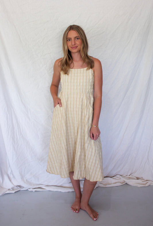 Woman wearing a white dress with thin straps against a white backdrop