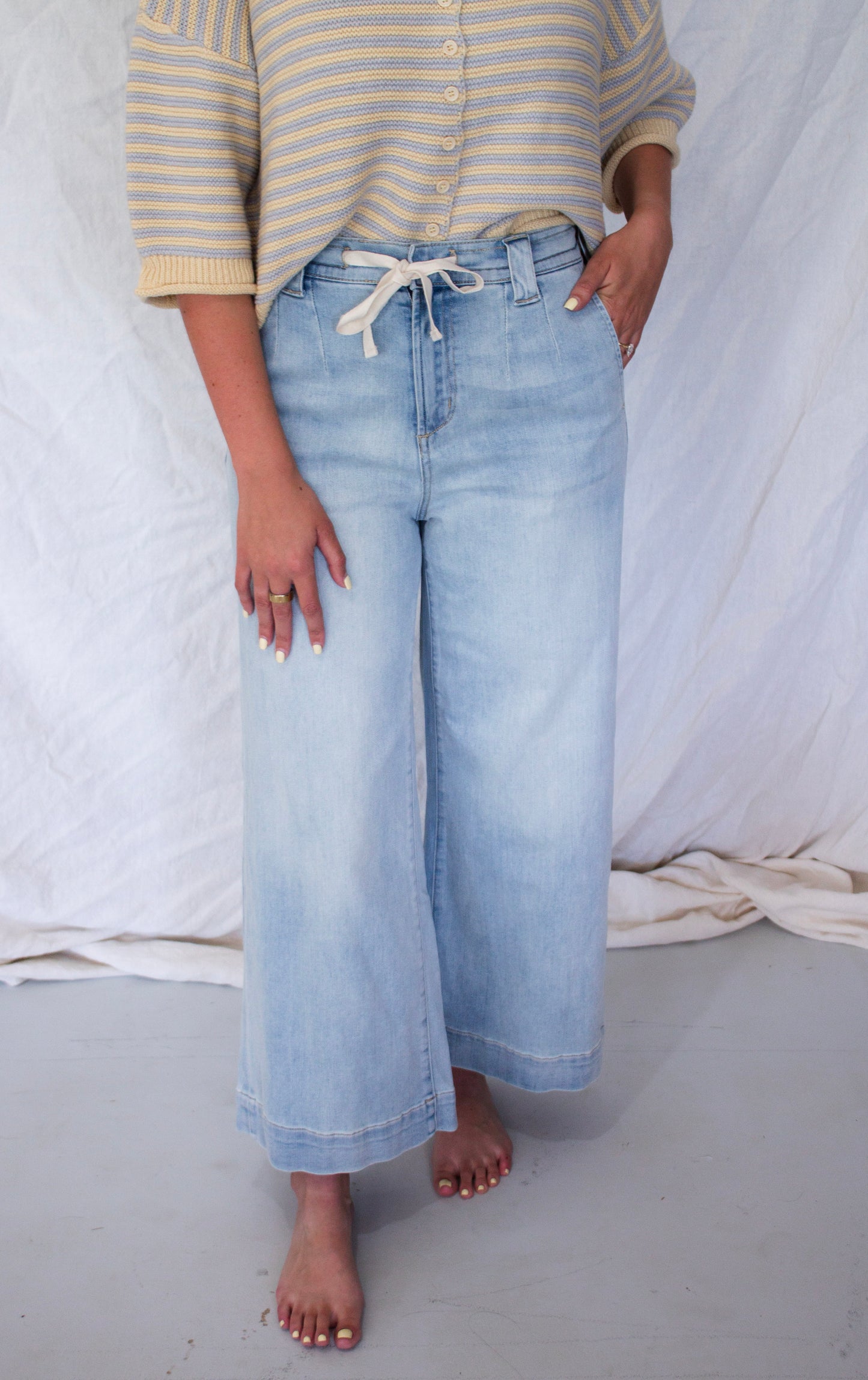 Person wearing light blue jeans and a striped shirt against a white background