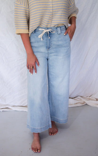 Person wearing light blue jeans and a striped shirt against a white background