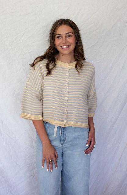 Woman wearing a striped shirt and jeans against a textured white background