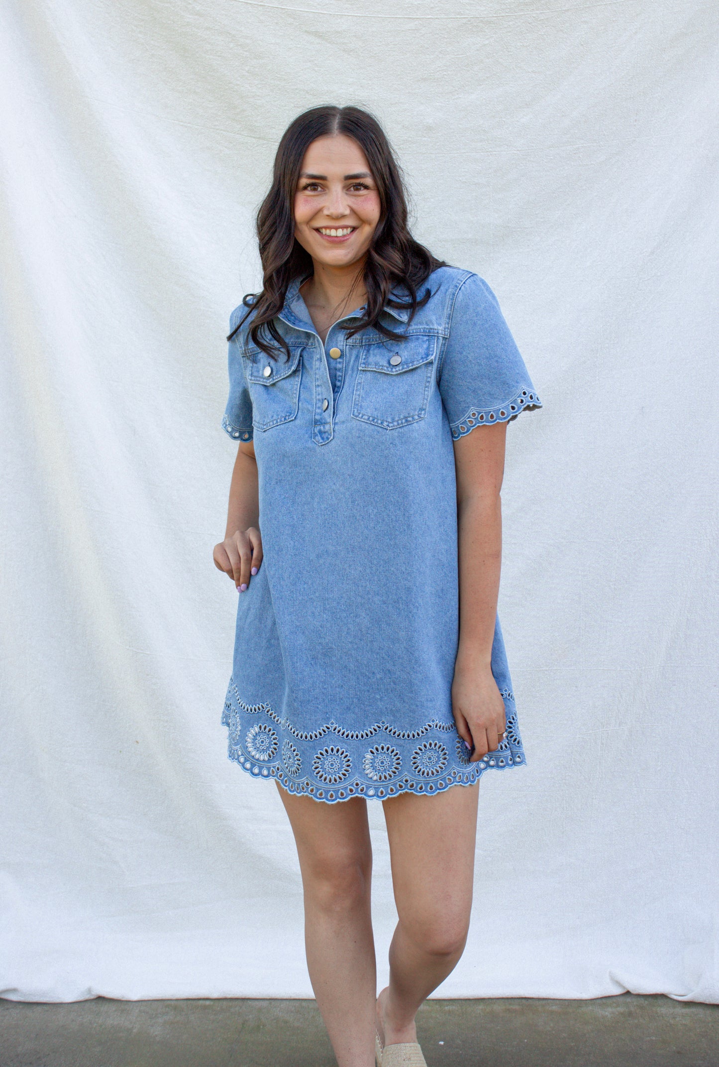 Woman wearing a denim dress with lace trim against a white background