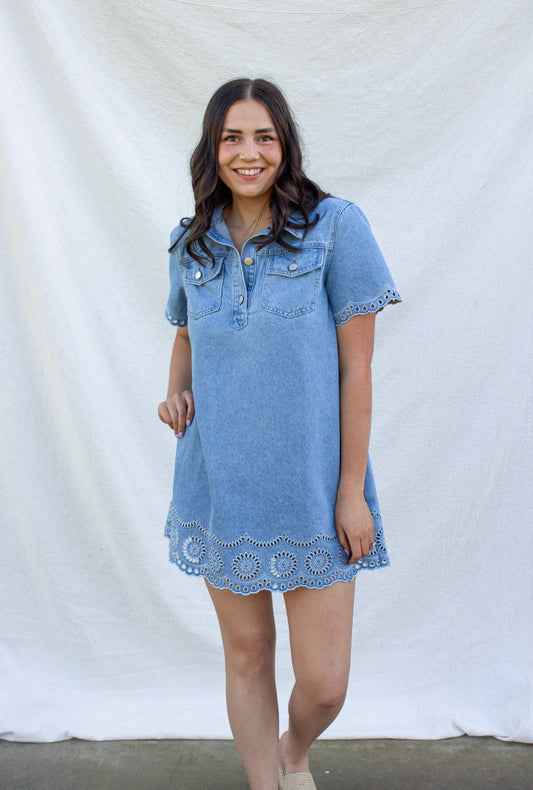 Woman wearing a denim dress with lace trim against a white background