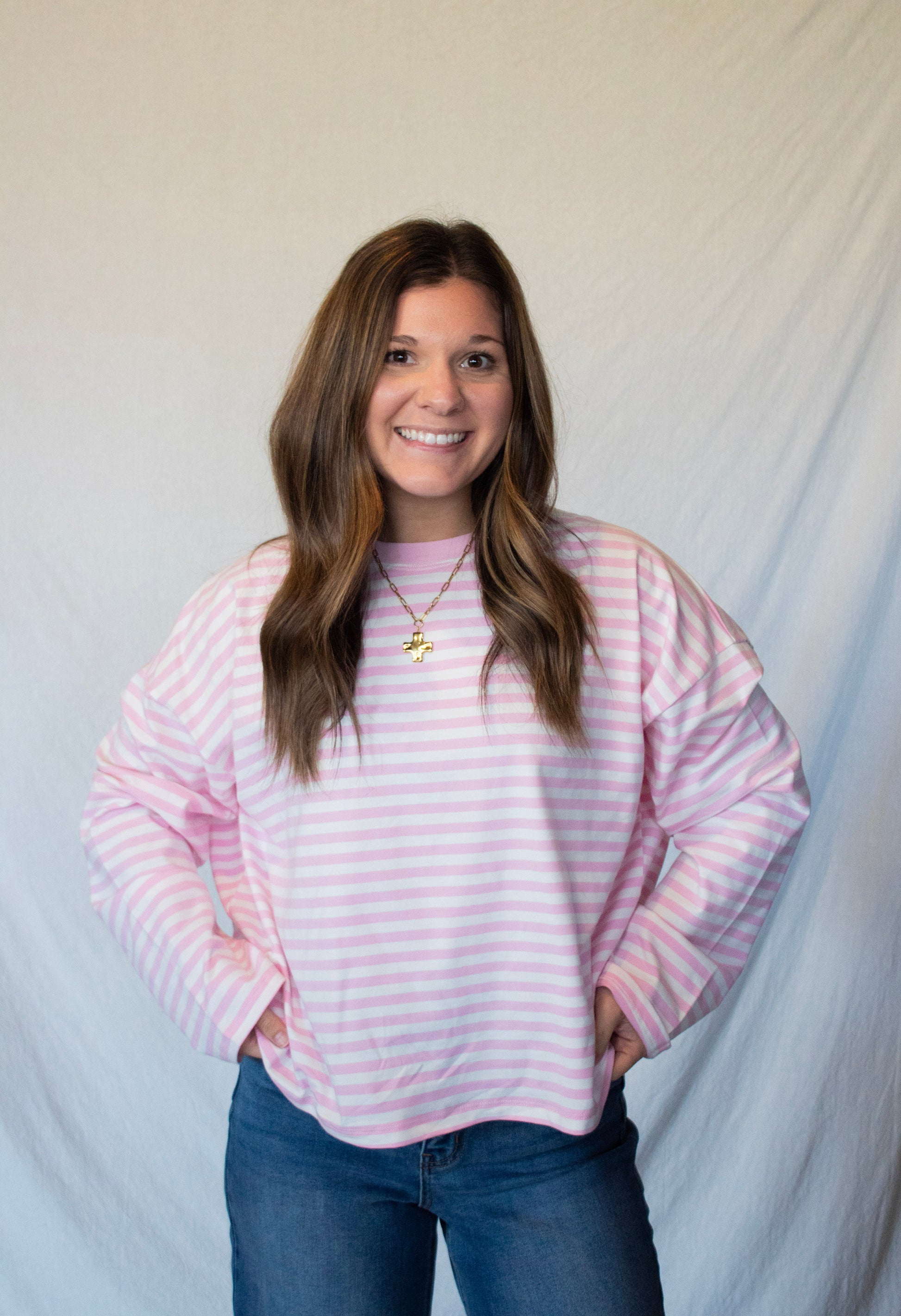 Woman wearing a pink and white striped sweater against a plain background