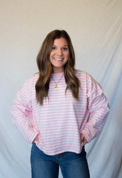 Woman wearing a pink and white striped sweater against a plain background