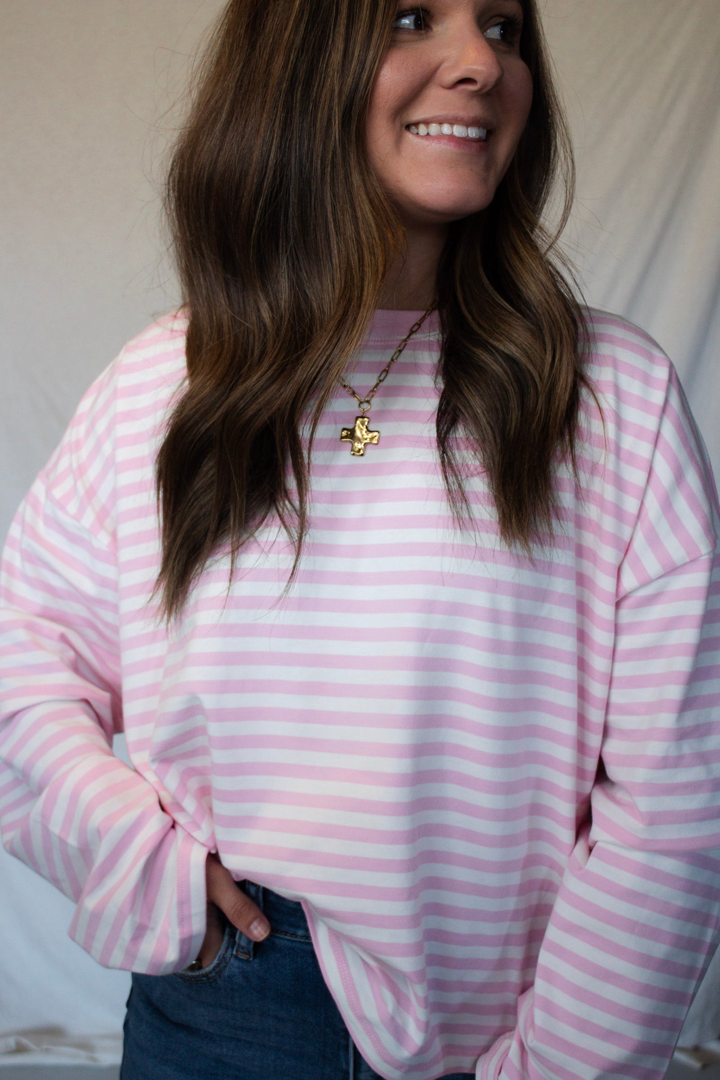 Person wearing a pink and white striped shirt with a neutral background