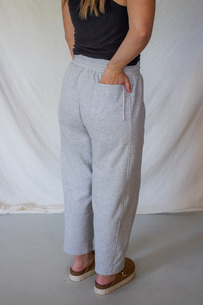 Person wearing gray sweatpants and a black top against a plain background