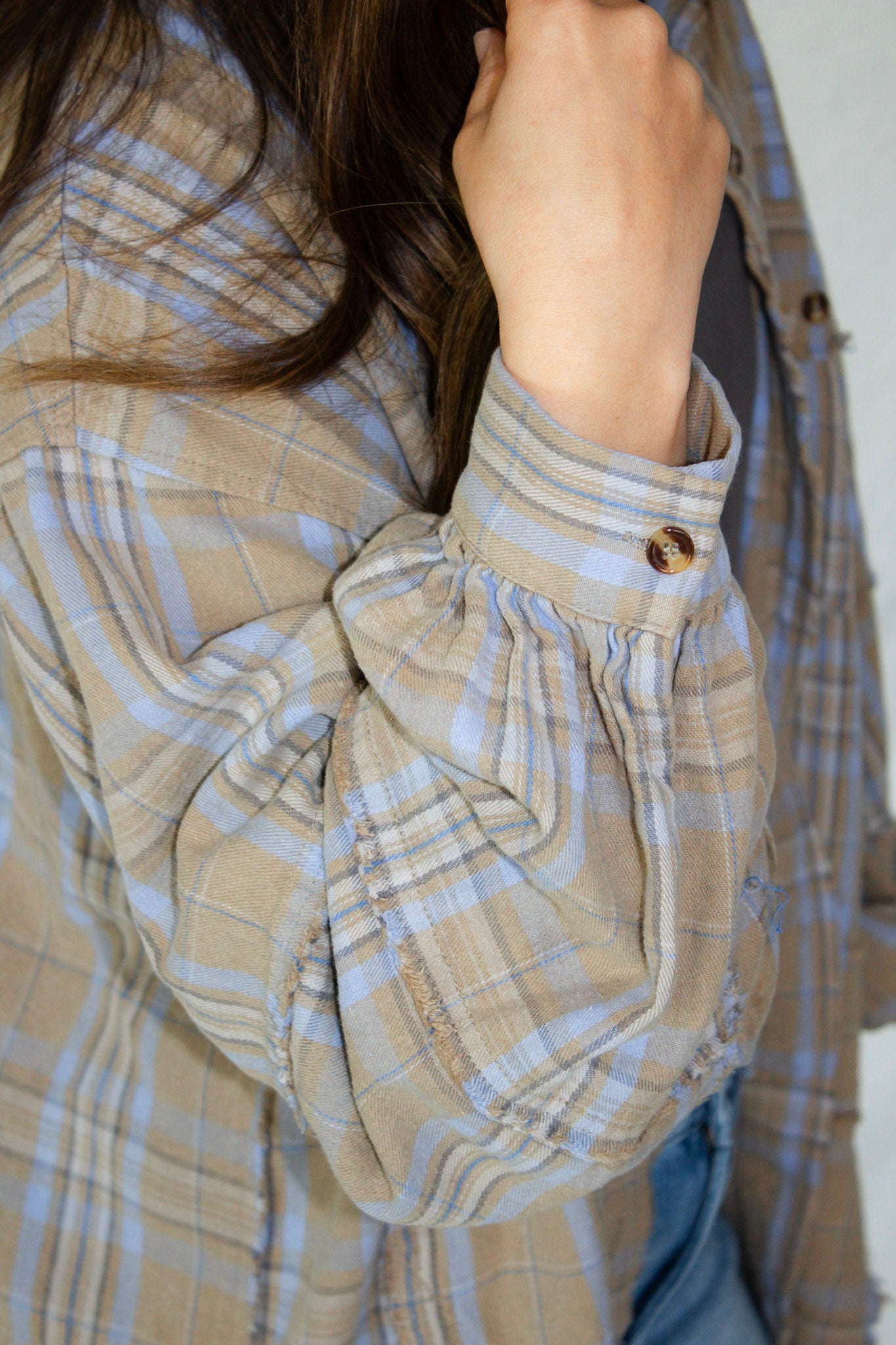 Close-up of a person wearing a plaid shirt with rolled-up sleeves.