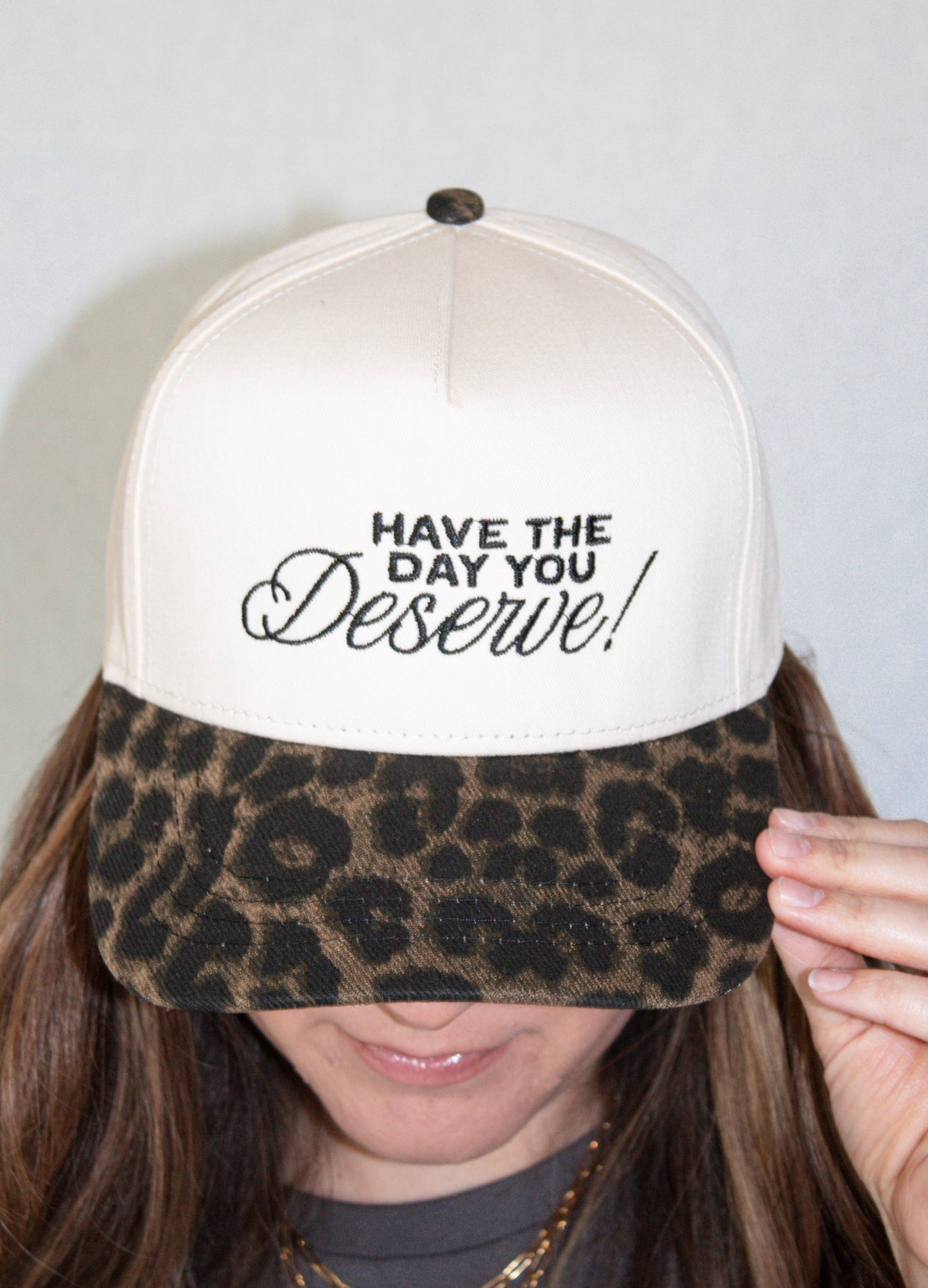 Trucker hat with leopard print brim and motivational text on a plain background