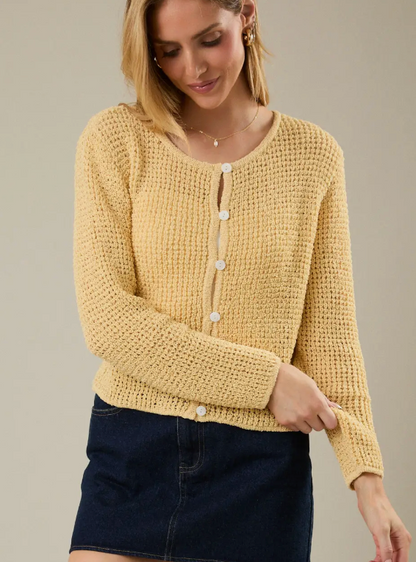 Woman wearing a yellow knitted cardigan against a neutral background